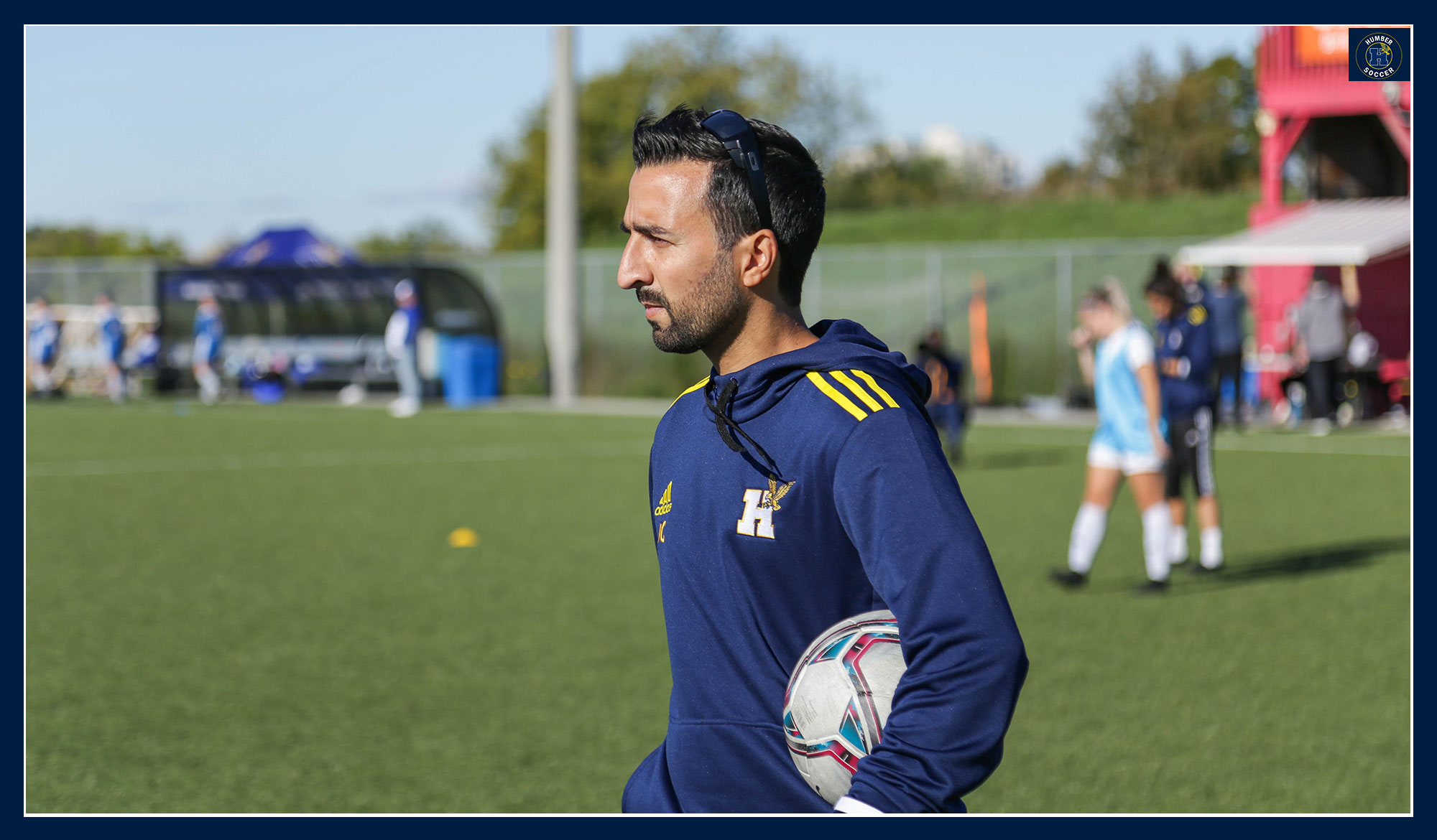 Coach Caro looking on at practice holding a soccer ball